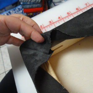 Glue seam line along a 45 degree angle. Fold extra fabric so it will meet the seam line and glue.